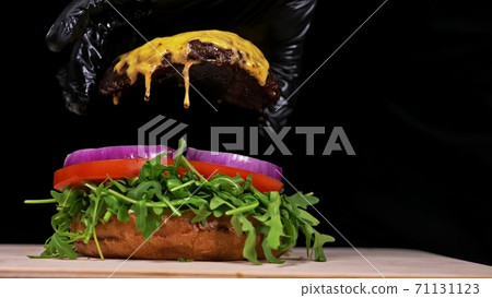 Craft burger is cooking on black background. Consist: sauce, arugula, tomato, onion, bacon, currant sauce, ricotta cheese, air bun and marble meat. 71131123