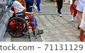 disabled man sitting on wheelchair waiting  for donations from people passed 71131129
