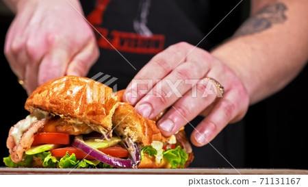 Cut craft burger is cooking on black background. Consist: sauce, lettuce, tomato, red onion, cucumber, cheese, bacon, air bun and breast of chicken. Cut craft burger is cooking on black background. Consist: sauce, lettuce, tomato, red onion, cucumber, cheese, bacon, air bun and breast of chicken. 71131167