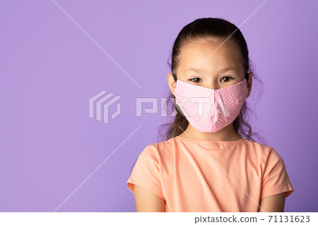 Girl in reusable mask isolated over purple studio wall Girl in reusable mask isolated over purple studio wall 71131623