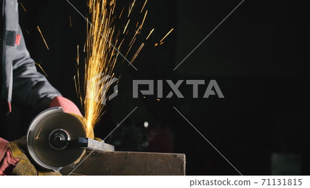 Forge workshop. Smithy manual production. Close up details of sparks, industrial worker using angle grinder and cutting steel. 71131815