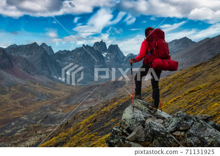 Woman Standing on Rocks looking at Scenic Mountain Peaks and Valley 71131925