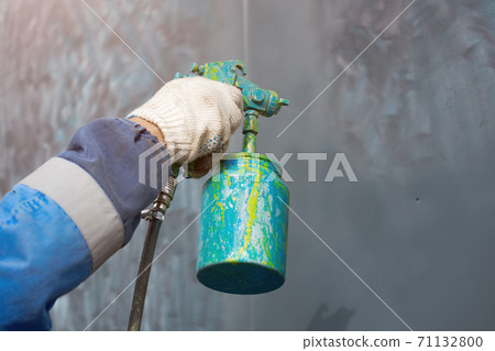 Metal surface painting. Hand with a compressor pultilizer close-up. 71132800