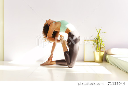 Flexible woman doing yoga at home 71133044