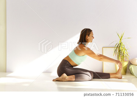 Flexible woman doing yoga at home 71133056