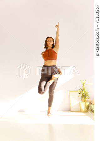 Flexible woman doing yoga at home 71133257