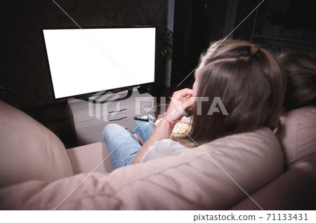 Young family of a man and a woman are lying on the sofa and watching TV. The TV screen is clipped in white. Mockup and template for design layout Young family of a man and a woman are lying on the sofa and watching TV. The TV screen is clipped in white. Mockup and template for design layout 71133431