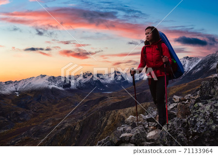 Woman Standing on Rocks looking at Scenic Mountain Peaks and Valley 71133964