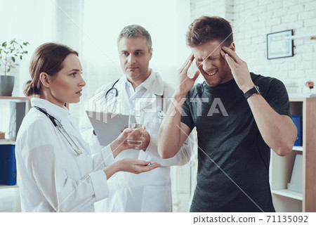 Doctors look at a suffering sportsman in office.  71135092