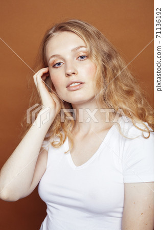young pretty girl with blond curly hair posing cheerful on brown background, lifestyle people concept 71136192