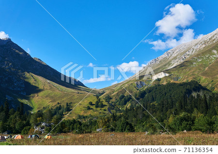 hiker camp in autumn meadow in front of a mountain pass hiker camp in autumn meadow in front of a mountain pass 71136354