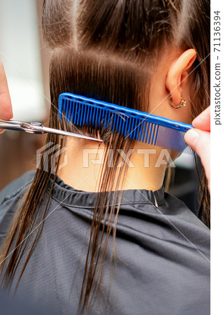 Hairdresser cuts off long hair of woman 71136394