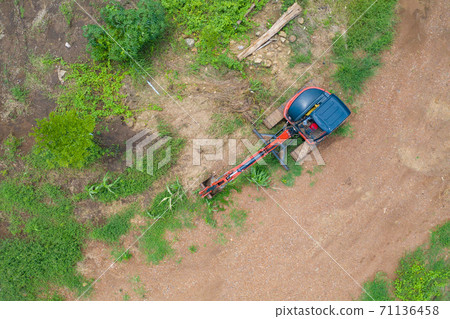 Aerial view of Construction tractor car, bulldozer, or backhoe digging road or street in transportation and agriculture concept. Engine working in grass farm field and land. 71136458