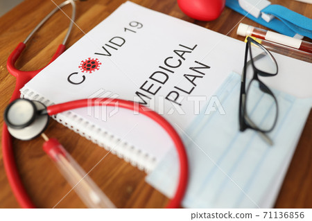 Medical journal with covid 19 sign lie on medical office table backround closeup Medical journal with covid 19 sign lie on medical office table backround closeup 71136856
