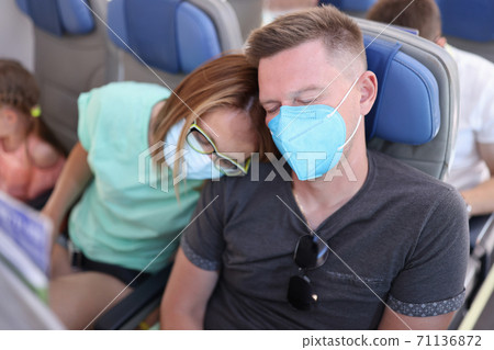 Man and woman in protective medical masks are sleeping on plane. Man and woman in protective medical masks are sleeping on plane. 71136872