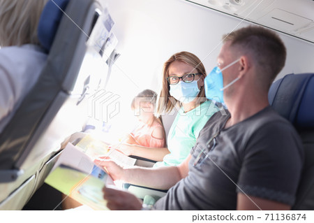 Man and woman are sitting on plane wearing medical protective masks Man and woman are sitting on plane wearing medical protective masks 71136874