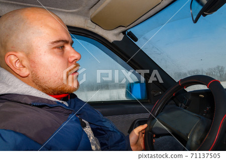 Young man driving a car on winter road. Inside view Young man driving a car on winter road. Inside view 71137505