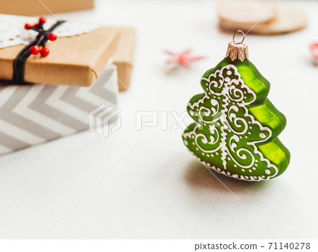 New Year decorations on white table. Christmas tree and wrapped presents. Winter holiday spirit. New Year decorations on white table. Christmas tree and wrapped presents. Winter holiday spirit. 71140278
