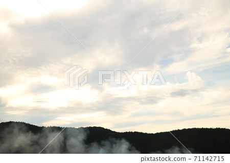 景觀與天空中的雲彩和遙遠的山脈中的煙 景觀與天空中的雲彩和遙遠的山脈中的煙 71142715