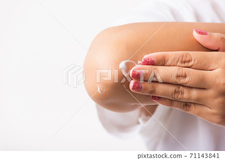 Woman applies lotion cream on her elbow Woman applies lotion cream on her elbow 71143841