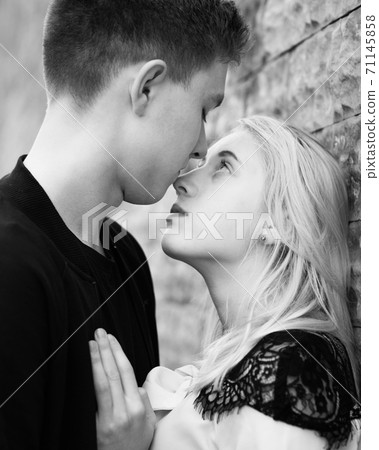 Close-up of young romantic couple is kissing near gray wall Close-up of young romantic couple is kissing near gray wall 71145858