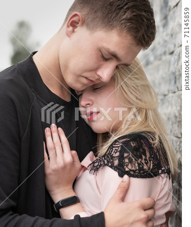 Close-up of young romantic couple is kissing near gray wall Close-up of young romantic couple is kissing near gray wall 71145859