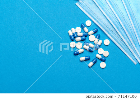 Protective medical face masks and pills on a blue background - Top view with copy space Protective medical face masks and pills on a blue background - Top view with copy space 71147100