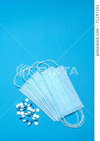Protective medical face masks and pills on a blue background - Top view with copy space Protective medical face masks and pills on a blue background - Top view with copy space 71147101