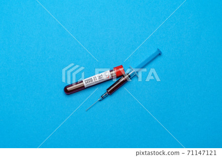 Syringe And Plastic Test Tube With Blood Sample over blue background with copyspace 71147121