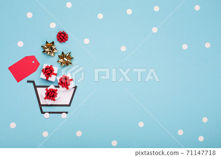 Super Sale day or Singles day concept. Shopping trolley, gift boxes and red tag on blue paper background. Super Sale day or Singles day concept. Shopping trolley, gift boxes and red tag on blue paper background. 71147718