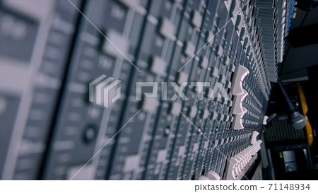 Close up of male sound engineer moves buttons of soundboard. Shot. Arms of man working on professional digital audio channel mixer. Amplifier and balance of sound. Close up of male sound engineer moves buttons of soundboard. Shot. Arms of man working on professional digital audio channel mixer. Amplifier and balance of sound. 71148934