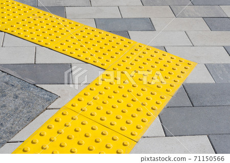 Yellow blocks of tactile paving for blind handicap. Braille blocks, tactile tiles for the visually impaired, Tenji blocks. Textured ground surface indicators located on sidewalks, stairs. 71150566