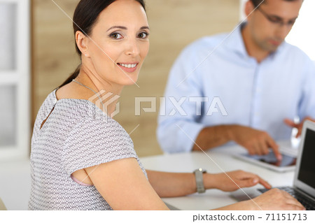 Business woman and businessman discussing questions while using a computer in modern office. Headshot of female hispanic entrepreneur at meeting. Group of diverse people. Teamwork, partnership and Business woman and businessman discussing questions while using a computer in modern office. Headshot of female hispanic entrepreneur at meeting. Group of diverse people. Teamwork, partnership and 71151713