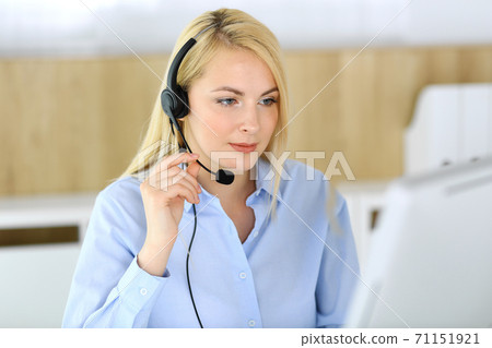 Call center. Blonde business woman sitting in headset at customer service office. Concept of telesales business or home office occupation Call center. Blonde business woman sitting in headset at customer service office. Concept of telesales business or home office occupation 71151921