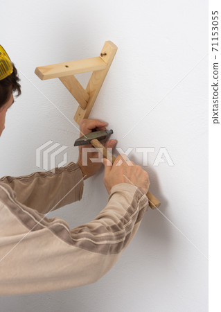Worker scores plastic anchor with a hammer Worker scores plastic anchor with a hammer 71153055