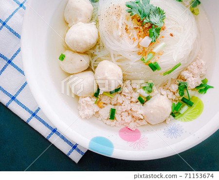 Clear Pork Noodle Soup Topped with pork balls Garnish with fried garlic and cilantro 71153674