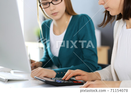 Accountant checking financial statement or counting by calculator income for tax form, hands close-up. Business woman sitting and working with colleague at the desk in office. Audit concept Accountant checking financial statement or counting by calculator income for tax form, hands close-up. Business woman sitting and working with colleague at the desk in office. Audit concept 71154078
