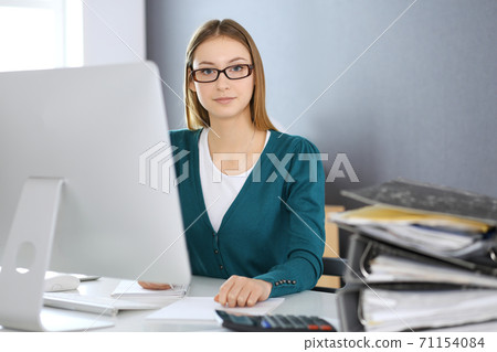 Accountant checking financial statement or counting by calculator income for tax form, hands close-up. Business woman sitting and working at the desk in office. Audit concept Accountant checking financial statement or counting by calculator income for tax form, hands close-up. Business woman sitting and working at the desk in office. Audit concept 71154084