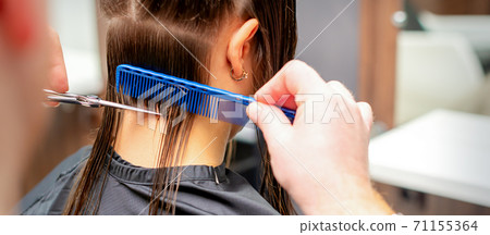 Hairdresser cuts off long hair of woman Hairdresser cuts off long hair of woman 71155364
