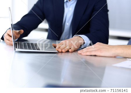 Business people using laptop computer while working together at the desk in modern office. Unknown businessman or male entrepreneur with colleague at workplace. Teamwork and partnership concept 71156141