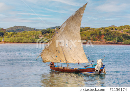 Malagasy fisher on sea in traditional handmade dugout wooden sailing boat Malagasy fisher on sea in traditional handmade dugout wooden sailing boat 71156174