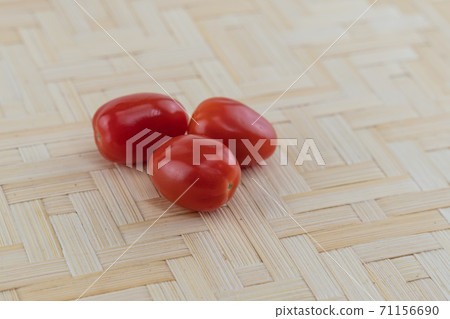 three little red cherry tomatoes lies on a wooden background three little red cherry tomatoes lies on a wooden background 71156690