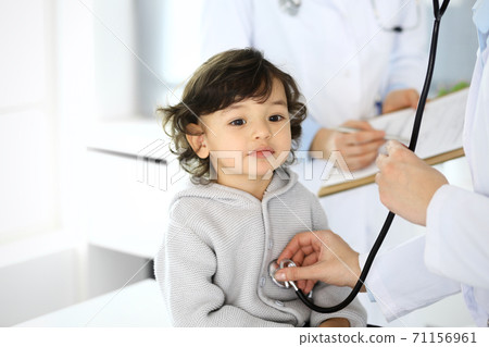 Doctor examining a child patient by stethoscope. Cute arab boy at physician appointment. Medicine and healthcare concept Doctor examining a child patient by stethoscope. Cute arab boy at physician appointment. Medicine and healthcare concept 71156961