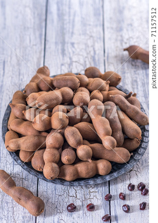 Bowl of fresh tamarinds on wooden table. 71157512