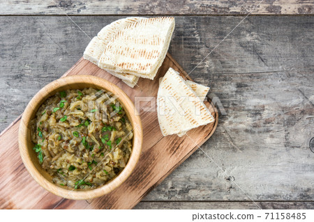 Baba ganoush in wooden bowl and pita bread on wooden table. Top view Baba ganoush in wooden bowl and pita bread on wooden table. Top view 71158485