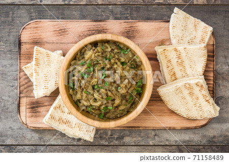 Baba ganoush in wooden bowl and pita bread on wooden table. Top view Baba ganoush in wooden bowl and pita bread on wooden table. Top view 71158489