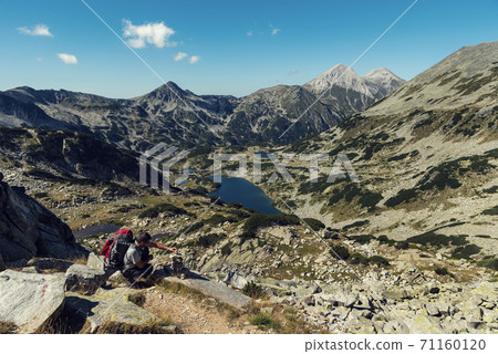 Young man making pyramid of stones in Pirin mountain in sunny summer day Young man making pyramid of stones in Pirin mountain in sunny summer day 71160120