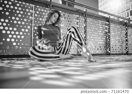 Black and white photo of a woman on a sunny balcony Black and white photo of a woman on a sunny balcony 71161470