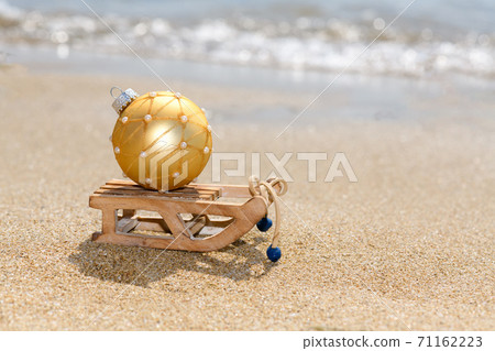 Christmas sleigh with golden ball on the tropical beach near ocean, Merry Christmas and Happy New Year background Christmas sleigh with golden ball on the tropical beach near ocean, Merry Christmas and Happy New Year background 71162223