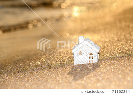 Closed up tiny home models on sand with sunlight and beach background. Closed up tiny home models on sand with sunlight and beach background. 71162224